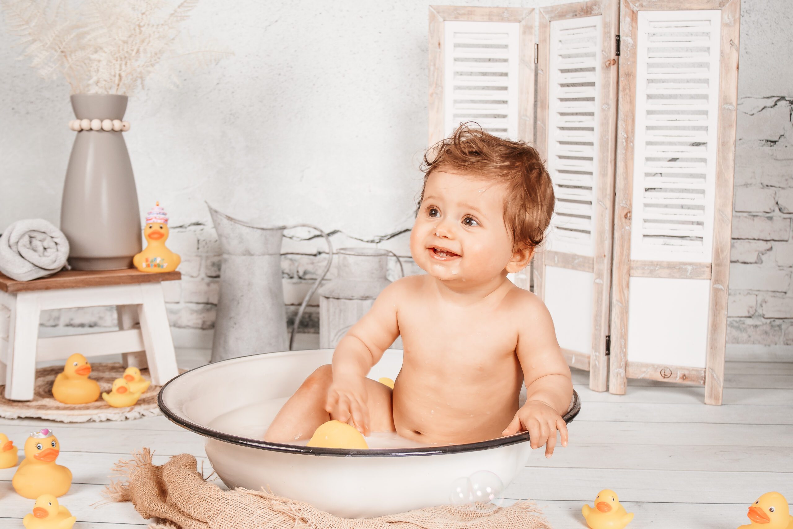 Baby beim Badeshooting im Milchbad mit Entchen